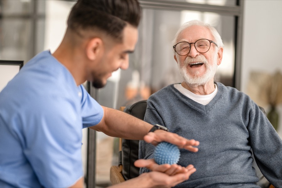 Physiotherapist and older patient laughing during a hand exercise
